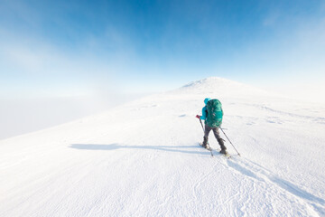 Fototapeta na wymiar A woman walks in snowshoes in the mountains, winter trekking