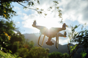 White drone with camera flying in summer mountains
