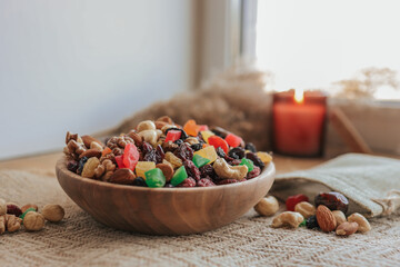 A plate with candied fruits and dried fruits on the table, against the backdrop of a candle