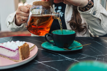 Girl in a cafe pours tea