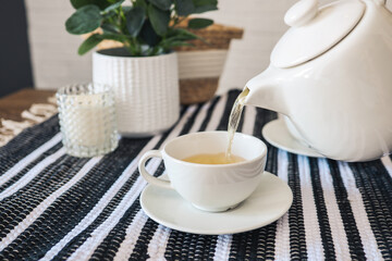 Teapot pours tea into a cup, tea drinking concept