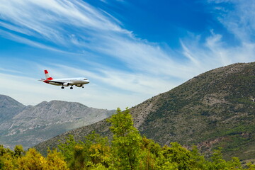 Fototapeta na wymiar Red-white color airplane landing in Dubrovnik airport (Cavtat).