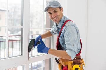 Construction worker installing window in house. Handyman fixing the window with screwdriver