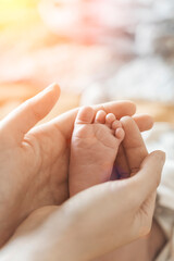Baby feet. Mom holds with tenderness and love in his hands the small legs of a newborn. New life, parental protection, care, love, child and baby health