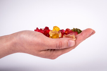 Red rubber candy bear in palm of woman on a white background