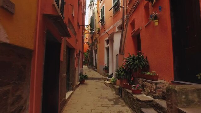 Walking through an ancient narrow street with stone road in Cinque Terre. Old town, architecture, color houses, narrow alleys in summer time.