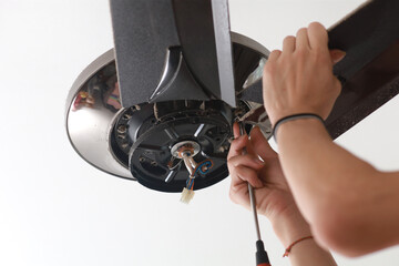 Close up a male electrician fixing and installing a ceiling fan in a house. - obrazy, fototapety, plakaty