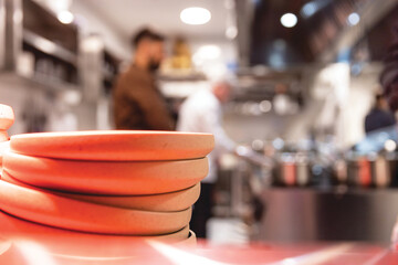 Blurred head chef of a restaurant kitchen cooking, plates in the focus