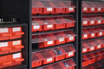 Screws, bolts, nuts, in red storage boxes in a workshop. Plastic organizer box.