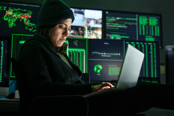 Female Hacker working in dark hidden hideout, attacking Company Data computer Servers and infecting system with Virus