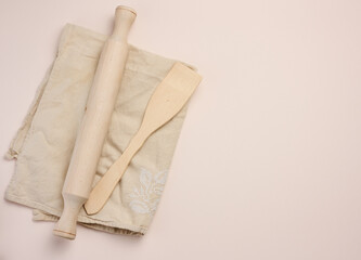 Wooden rolling pin for rolling dough on a beige background, top view. Copy space