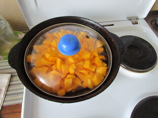 Yellow pieces of pumpkin on the frying pan shut with cover