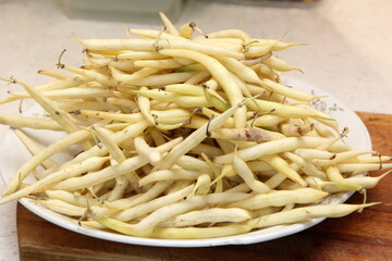 Fresh butter beans on a plate. Close up of yellow string beans in a white bowl