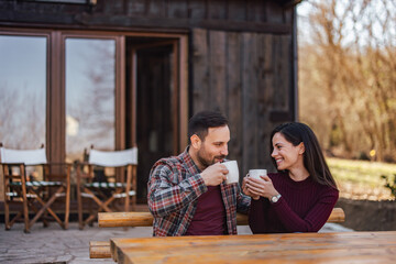 Smiling lovers, enjoying themselves together, drinking coffee, sitting outside.