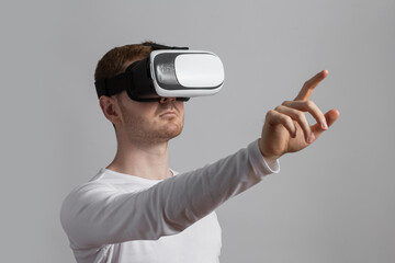 Modern young man experiencing virtual reality glasses in studio