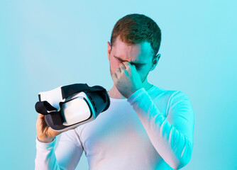 Modern young man experiencing virtual reality glasses in futuristic neon illuminated studio