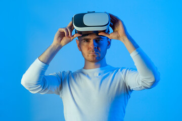 Modern young man experiencing virtual reality glasses in futuristic neon illuminated studio