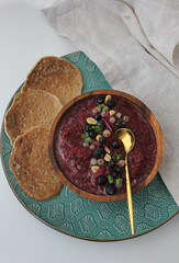 purple berry smoothie bowl in a wooden bowl and healthy green buckwheat pancakes
