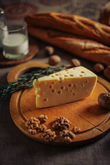 Triangle of cheese with holes masdaam on the board composition with nuts, milk, baguettes for cheese makers