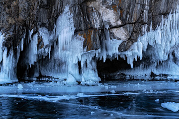 Beautiful winter landscape with blue ice cave grotto and frozen clear icicles. Lake Baikal, Olkhon island, Russia. Natural winter background.