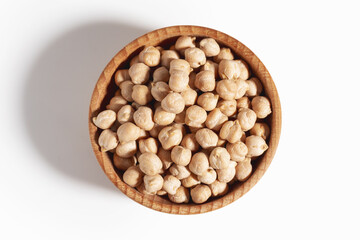 Wooden bowl filled with chickpea beans. Chickpea beans in bowl isolated on white background. View top.