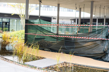 Fototapeta premium Red lanterns and a protective tape at the road repair sector. Compliance with safety measures at night and in the daytime when performing repair work on the city streets.