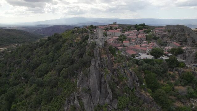 Castle of Sortelha on top of steep cliff; drone arc shot reveals landscape