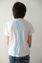 part of naked back of boy, child 10 years old in a white t-shirt bent over from back pain, concept...