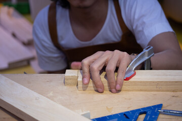 Close-up of a carpenter using a clamp on a large board of wood.