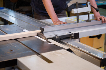 A man is using a circular saw to cut a large board of wood. Construction works. Finishing work.