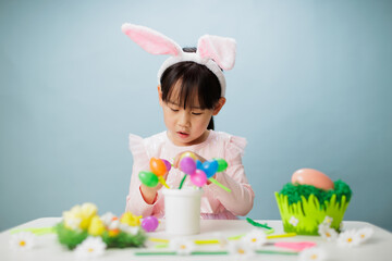 young girl making easter craft against plain background