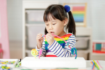 young girl threading beads making craft for home schooling