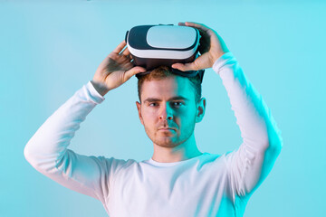 Modern young man experiencing virtual reality glasses in futuristic neon illuminated studio