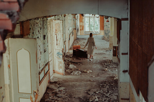 A woman in a dress from the back in an abandoned destroyed building
