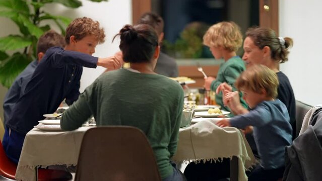 Candid family united around dinner table at night parents and children together around meal