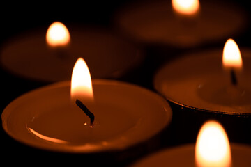 Cup candles that are lit in the dark, holy light,Burning candles on dark surface. Memory day