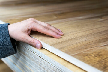 buyer's hand selects a thick sheet of laminated plywood in a store