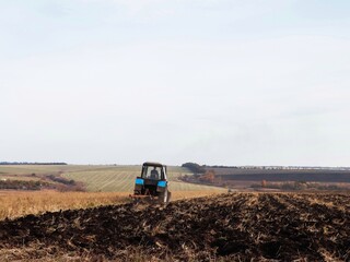 Blue tractor plows the field with a plow