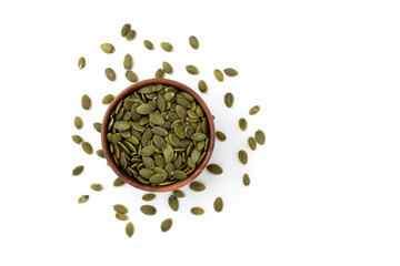bowl of green pumpkin seeds on white background, top view