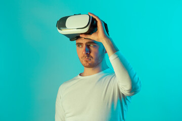 Modern young man experiencing virtual reality glasses in futuristic neon illuminated studio