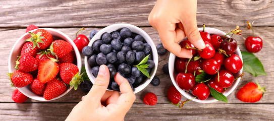 berries fruits assorted and hand holding blueberry and cherry fruit