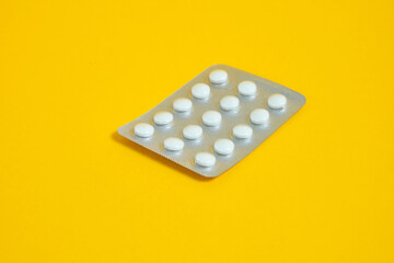 blister with pills on a yellow background close-up