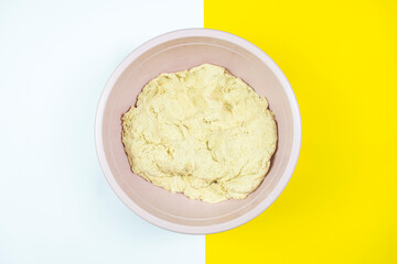 Kneaded pastry in plastic case, isolated on white and yellow background, pastry for bread with copy space, making bread concept, top view