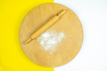 Rolling pin on traditional circle wooden board, top view of roller and some flour, making homemade bread, cooking concept, copy space