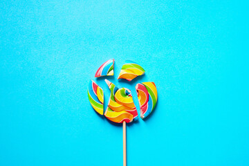 Multi-colored lollipop is divided into several parts. On a blue background. Space copy.