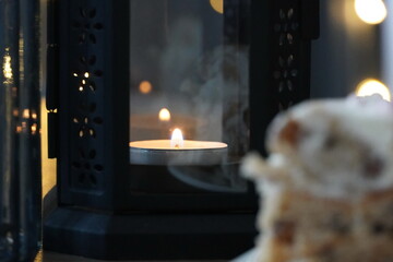 The flame of a burning candle in a lamp on the dining table