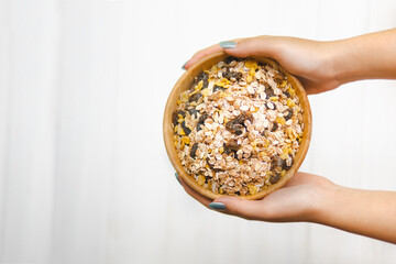 hand woman holding muesli in wood cup