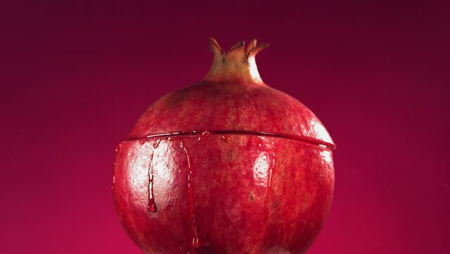 Half Pomegranate falling and splashing on fuchsia background. Food levitation concept. Slow Motion
