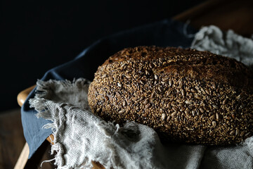Craft bread on a linen tablecloth. Sourdough bread. Sour bread. Whole grain bread. Dark mood.