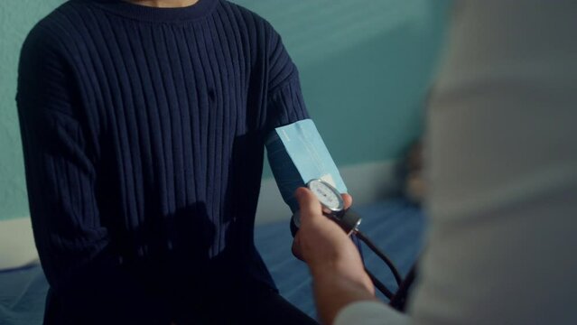 Doctor checking arterial pressure using tonometer on african girl arm close up.